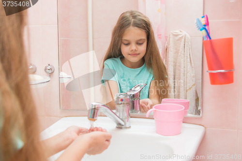 Image of  Girl pours her hands tap water in the bathroom