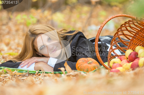 Image of Young girl lies on the on the foliage in the autumn forest