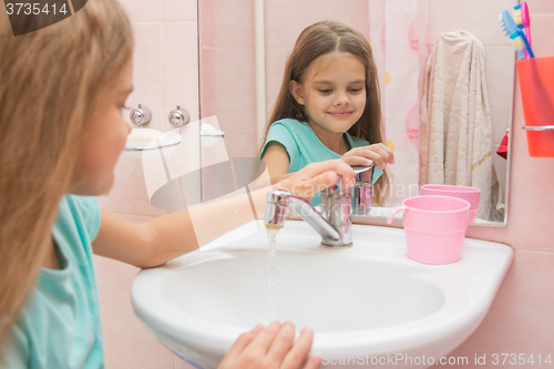 Image of Girl closes after washing the mixer tap in the bathroom