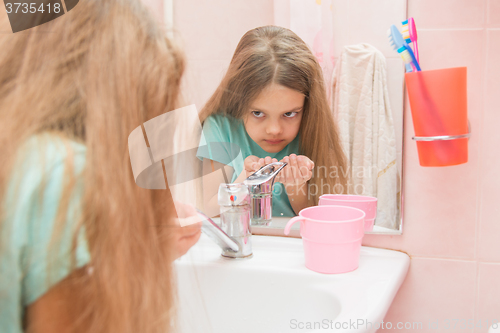Image of The girl washing up looked in the mirror in the bathroom