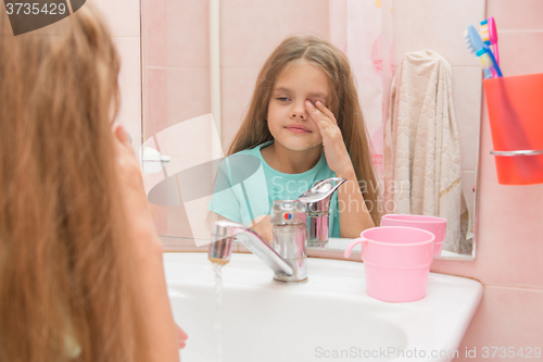 Image of Girl wet hand wipes the sleep from his eyes in the bathroom