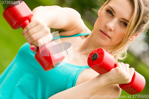 Image of Sports girl exercise with dumbbells in the park