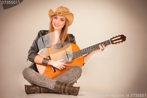 Image of The beautiful girl in a cowboy\'s hat and acoustic guitar.