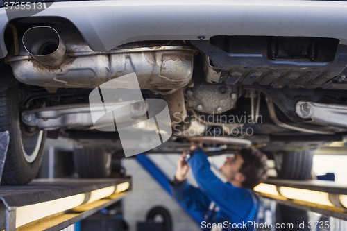 Image of Exhaust of a car with mechanic underneath