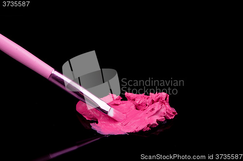 Image of lipstick with a brush make-up on black 