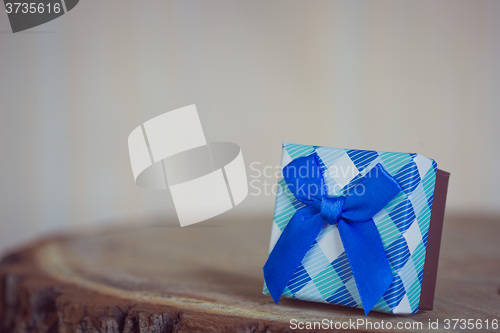 Image of Gift box with red bow on wood background