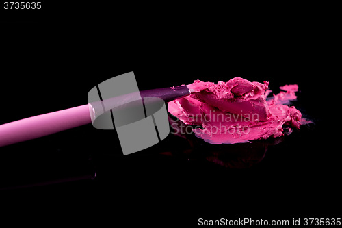 Image of lipstick with a brush make-up on black 