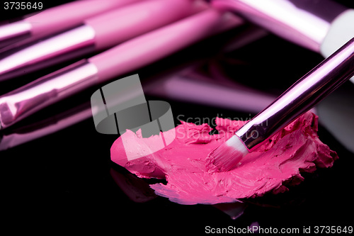Image of lipstick with a brush make-up on black 