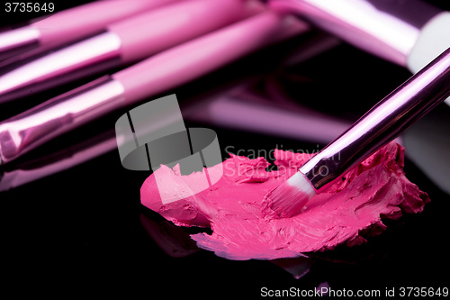 Image of lipstick with a brush make-up on black 