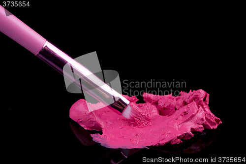 Image of lipstick with a brush make-up on black 