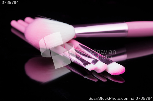 Image of pink make-up brushes isolated on black background.