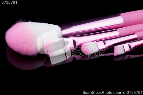 Image of pink make-up brushes isolated on black background.