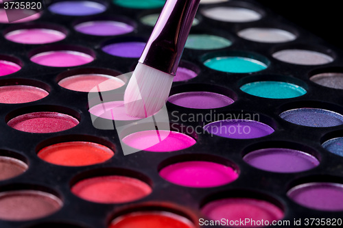Image of Colorful eye shadows palette with makeup brush.