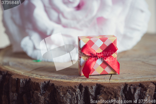 Image of Gift box with red bow on wood background