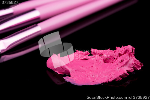 Image of lipstick with a brush make-up on black 