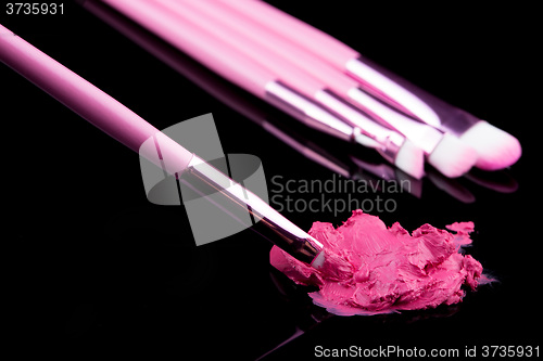 Image of lipstick with a brush make-up on black 