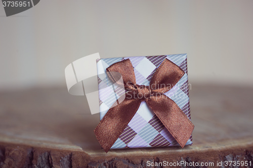 Image of Gift box with red bow on wood background