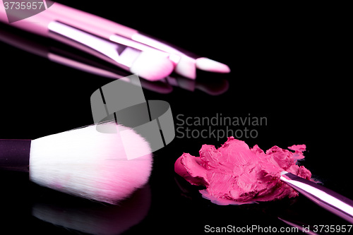 Image of lipstick with a brush make-up on black 