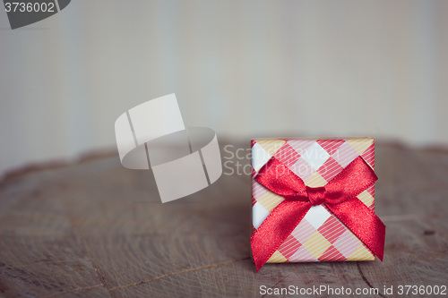 Image of Gift box with red bow on wood background