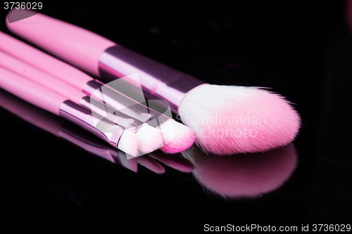 Image of pink make-up brushes isolated on black background.