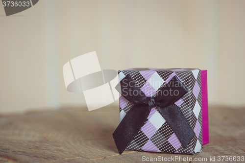 Image of Gift box with red bow on wood background