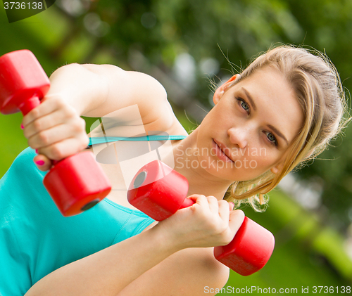 Image of Sports girl exercise with dumbbells in the park