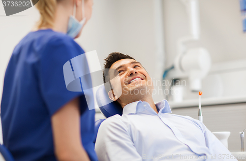 Image of female dentist with happy male patient at clinic