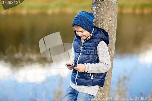 Image of happy boy playing game on smartphone outdoors