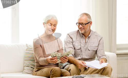 Image of senior couple with money and calculator at home