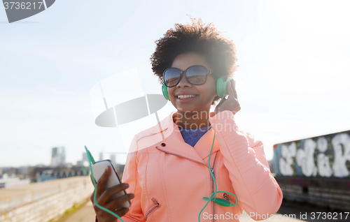Image of happy young woman with smartphone and headphones
