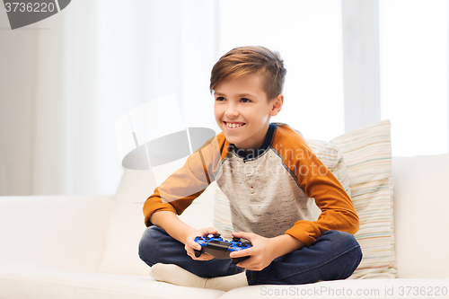 Image of happy boy with joystick playing video game at home