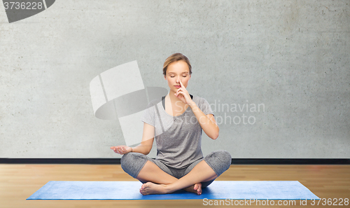 Image of woman making yoga meditation in lotus pose on mat