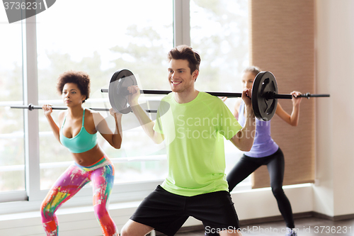 Image of group of people exercising with barbell in gym