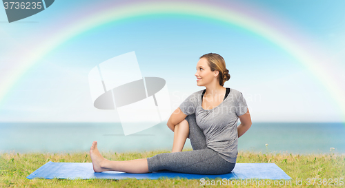 Image of woman making yoga in twist pose on mat