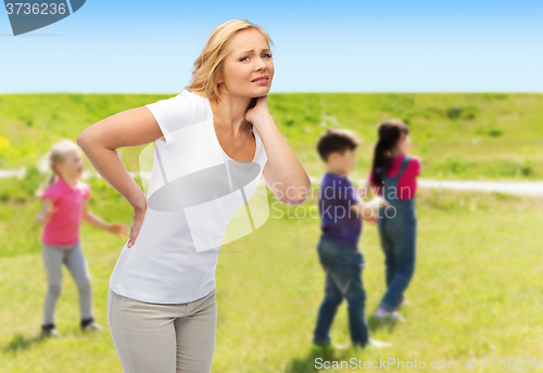 Image of woman suffering from backache over group of kids