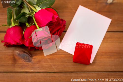 Image of close up of gift box, red roses and greeting card