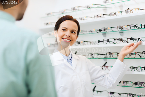 Image of optician showing glasses to man at optics store