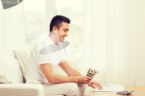 Image of man with papers and calculator at home