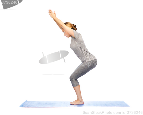 Image of woman making yoga in chair pose on mat