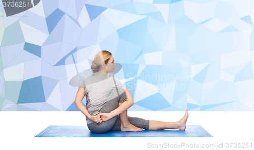 Image of woman making yoga in twist pose on mat