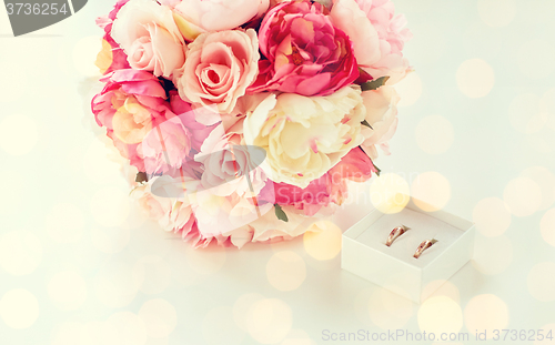 Image of close up of two wedding rings and flower bunch