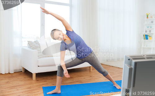 Image of woman making yoga bikram triangle pose on mat