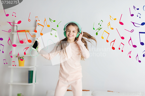 Image of girl jumping on bed with smartphone and headphones