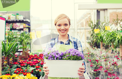 Image of happy woman holding flowers in greenhouse