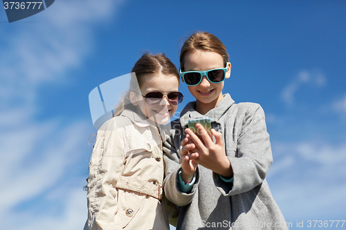 Image of happy girls with smartphone taking selfie outdoors