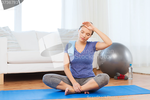 Image of tired woman with towel after workout at home