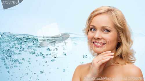 Image of smiling woman with bare shoulders touching face