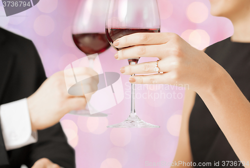 Image of happy engaged couple clinking wine glasses