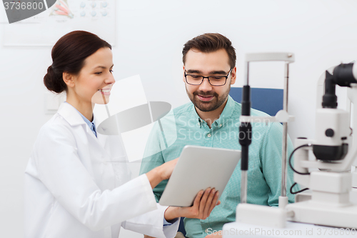 Image of optician with tablet pc and patient at eye clinic