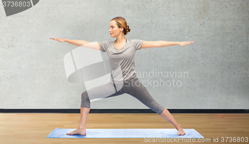 Image of woman making yoga warrior pose on mat